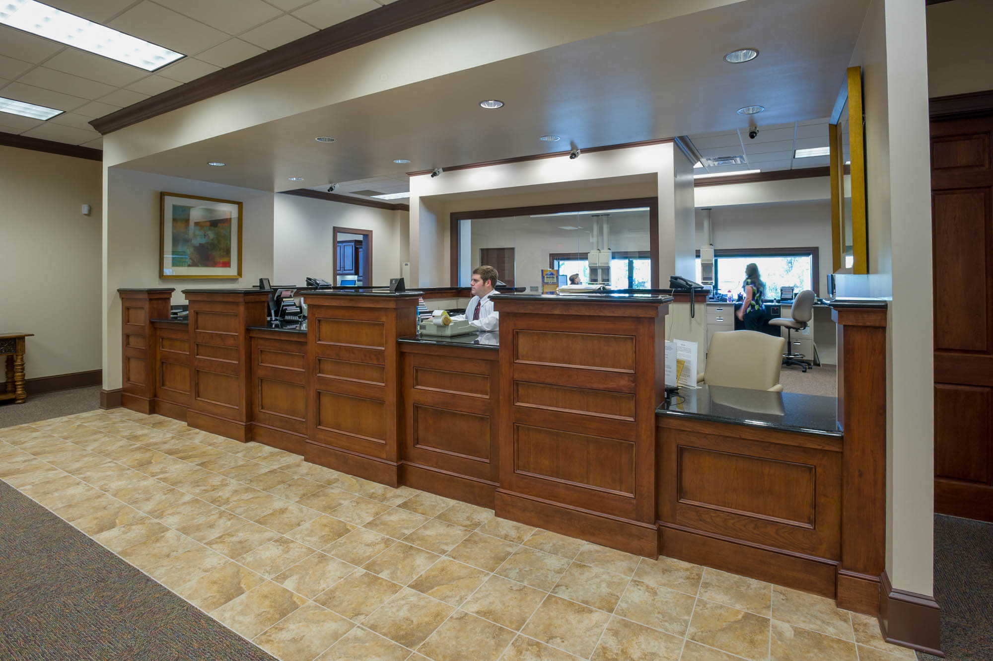 Teller counter made of rich wood with glass partitions separating workstations