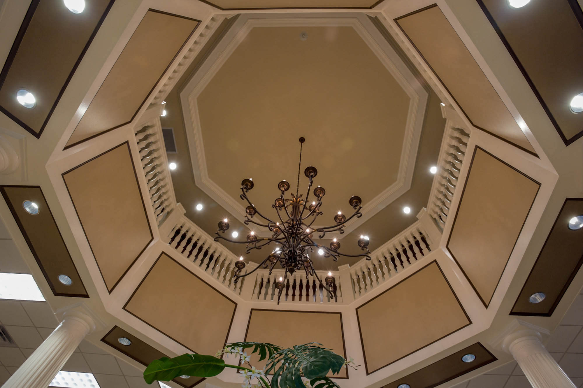 Upward view of an octagonal coffered ceiling with balustrade, skylight and chandelier