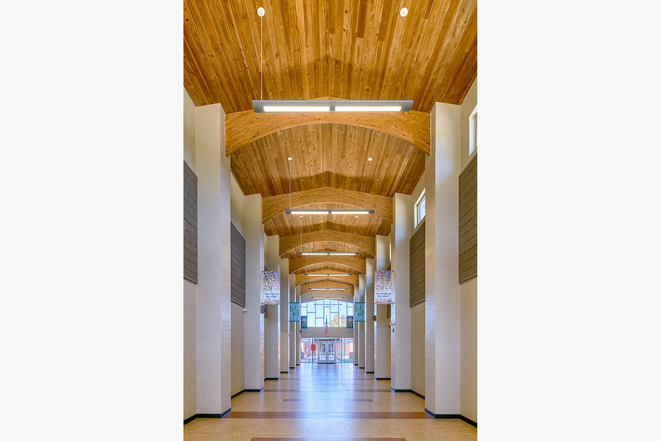 Corridor featuring an arched wooden ceiling supported by tall columns