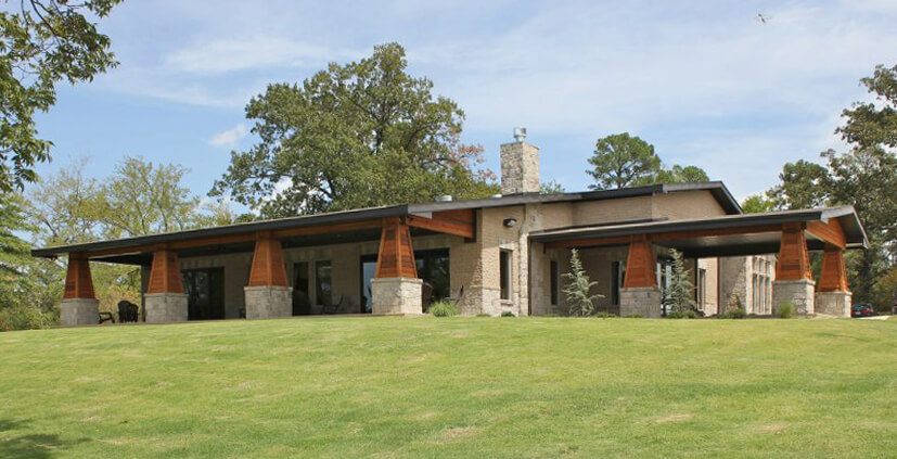Angled exterior view of WolfLife Campus Ministry Building with stone columns, wood accents, and central chimney