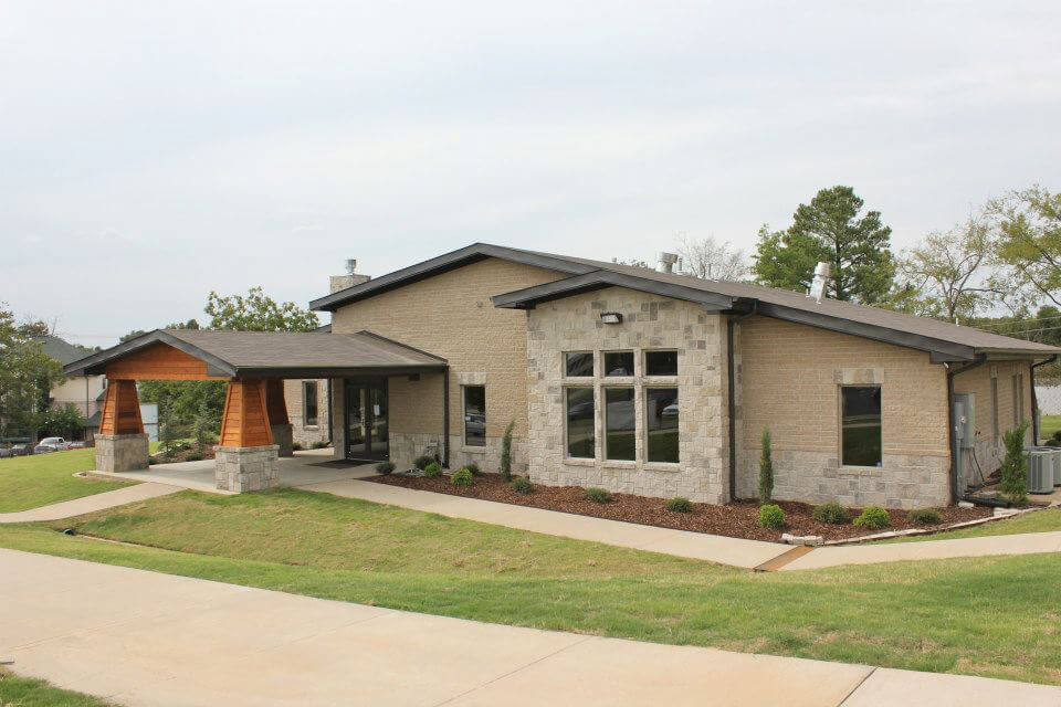 Front entrance of WolfLife Campus Ministry Building with stone and brick exterior, covered drive, and landscaped walkway